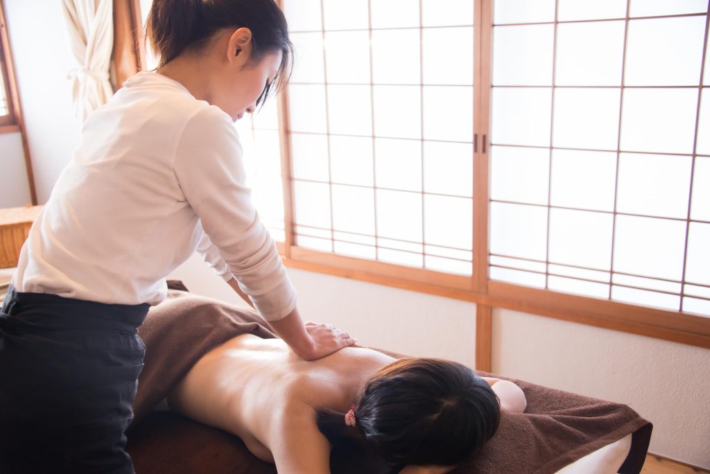 女性が女性の背中をハンドマッサージしている